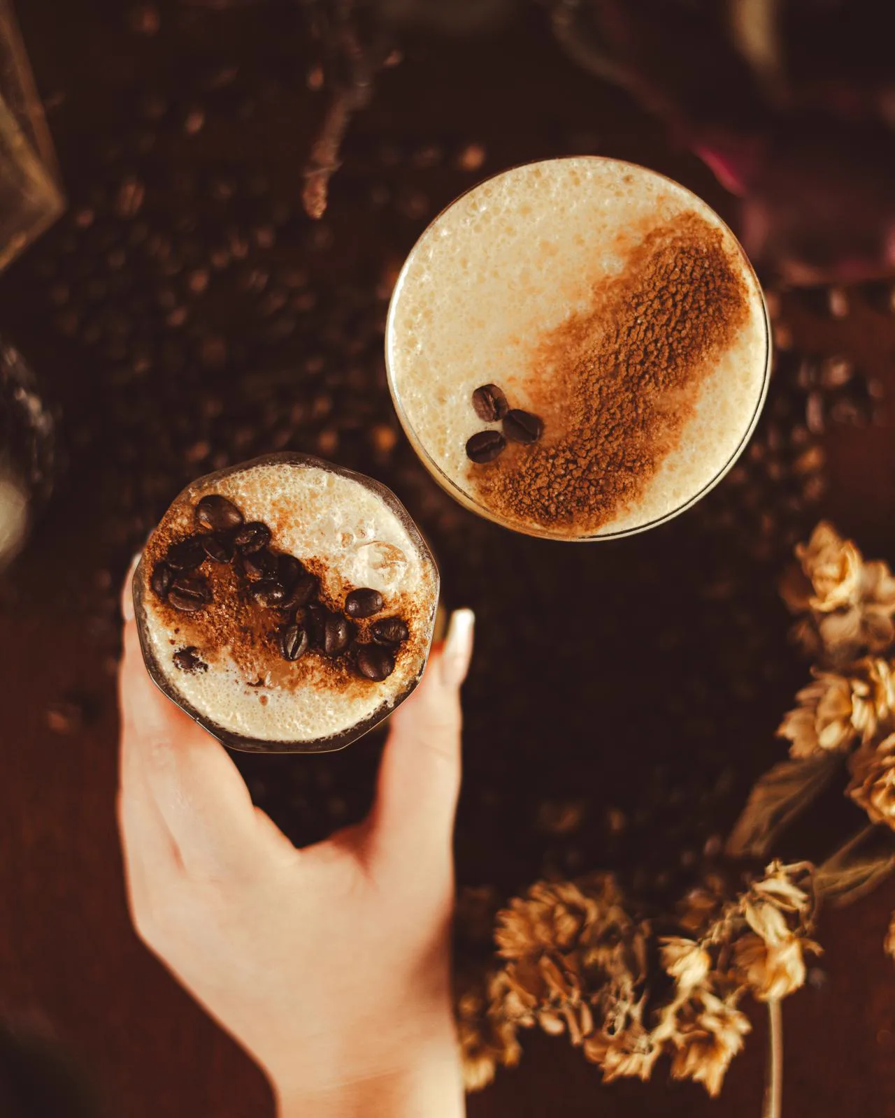 Two espresso martinis dusted with cocoa, coffee beans scattered on the table