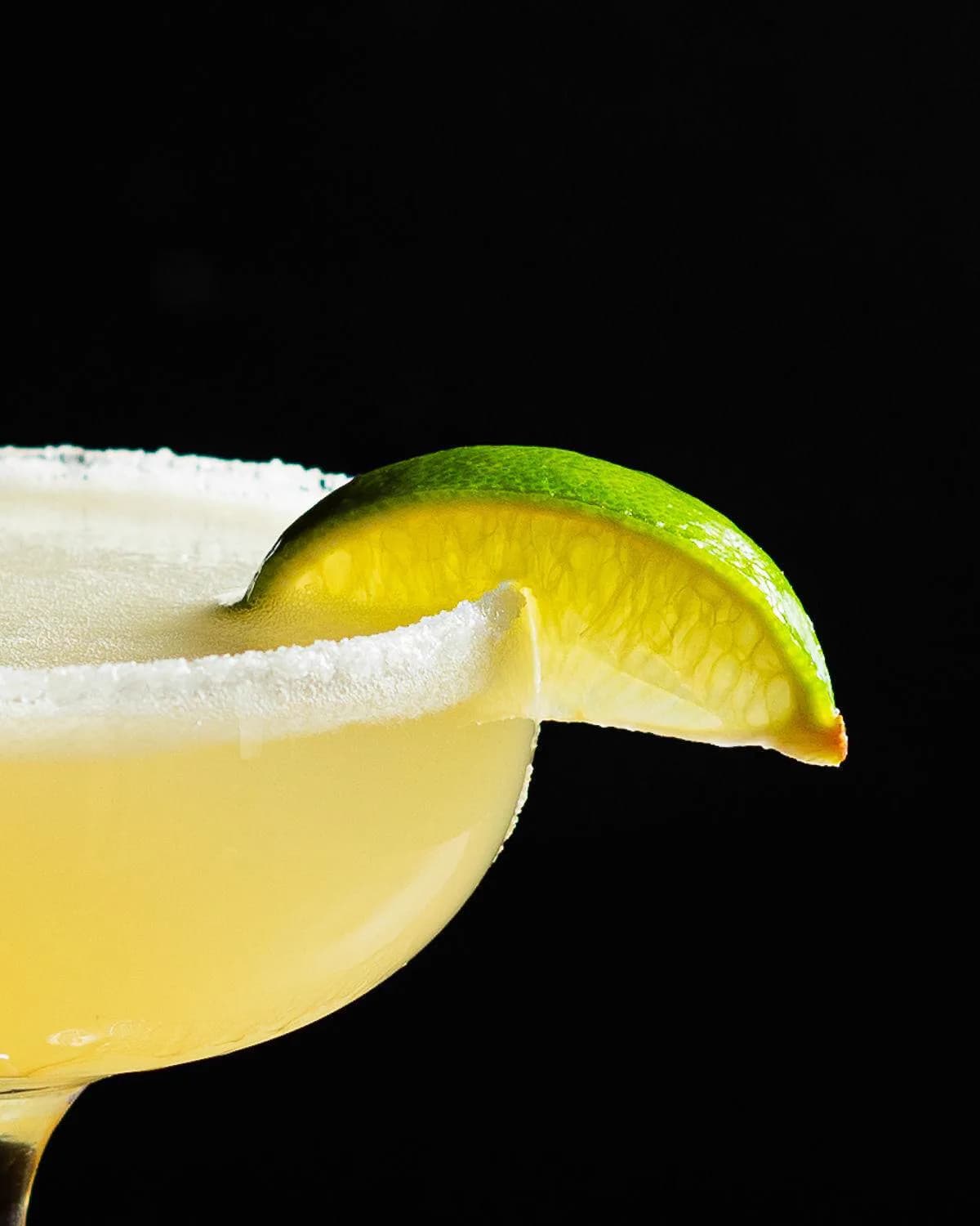 A salt-rimmed margarita with a lime wedge